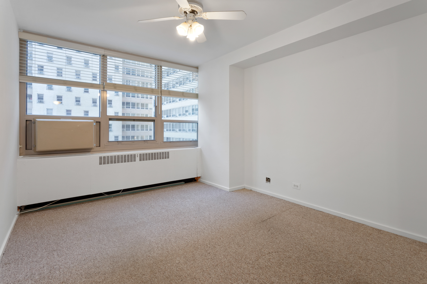 3950 North Lake Shore Drive, Unit 1006B Chicago, IL 60613 - Photo 11 of 12 an empty room with chandelier fan and windows