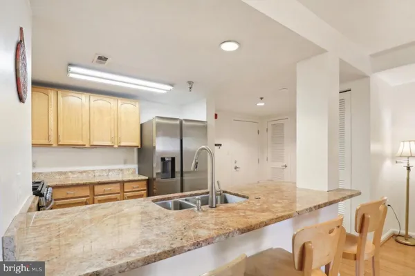 a view of a kitchen with kitchen island granite countertop wooden floor and a sink