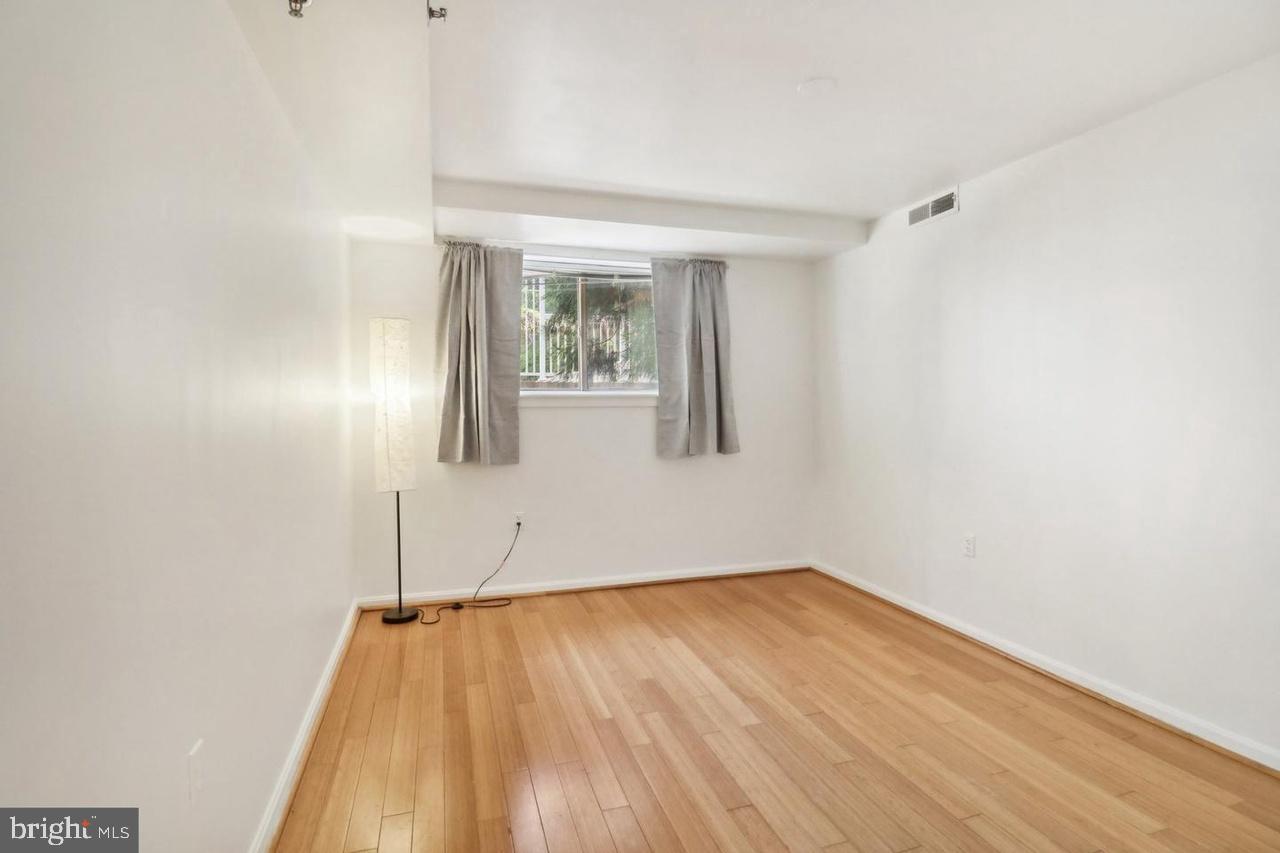 7981 Eastern Avenue Northwest, Unit 211 Silver Spring, MD 20910 - Photo 41 of 50 a view of an empty room with wooden floor and a window