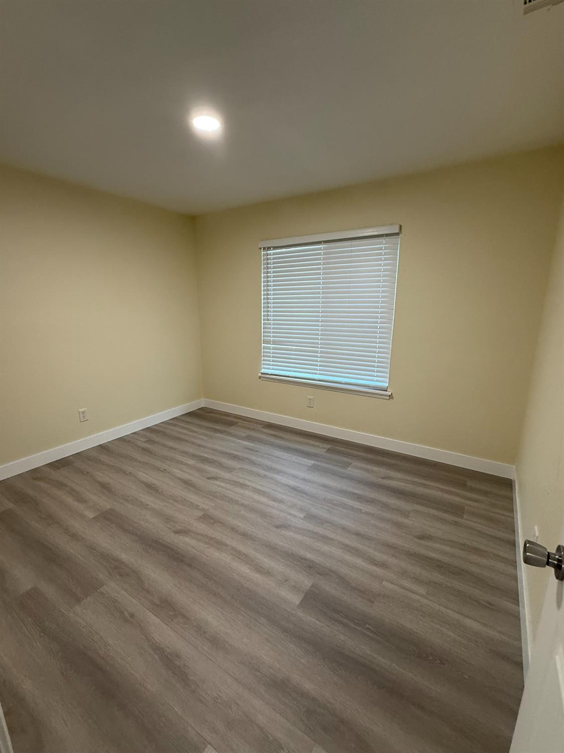1909 Wagner Heights Road Stockton, CA 95209 - Photo 4 of 12 an empty room with wooden floor and windows
