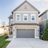 a front view of a house with yard and parking