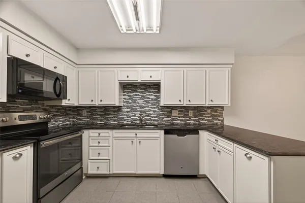a kitchen with stainless steel appliances granite countertop a sink and dishwasher a stove top oven with white cabinets