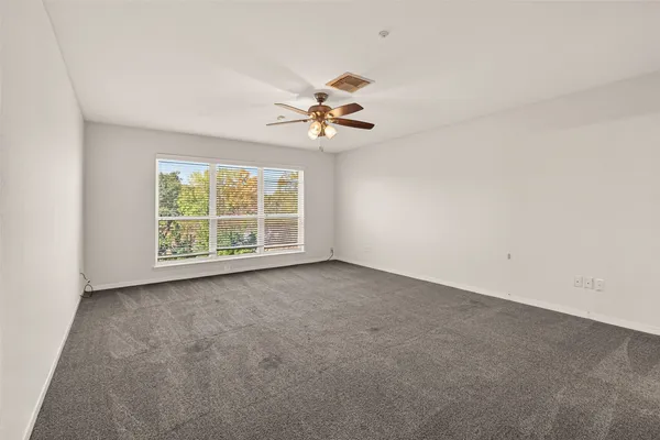 an empty room with a chandelier fan and windows