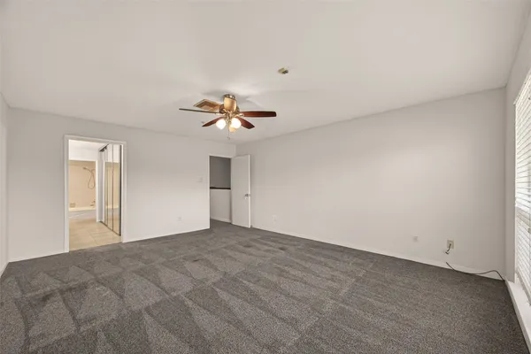 a view of an empty room with a chandelier fan