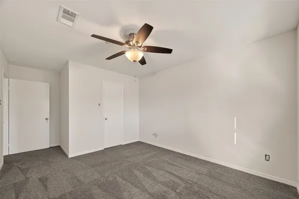 an empty room with a window and a fan