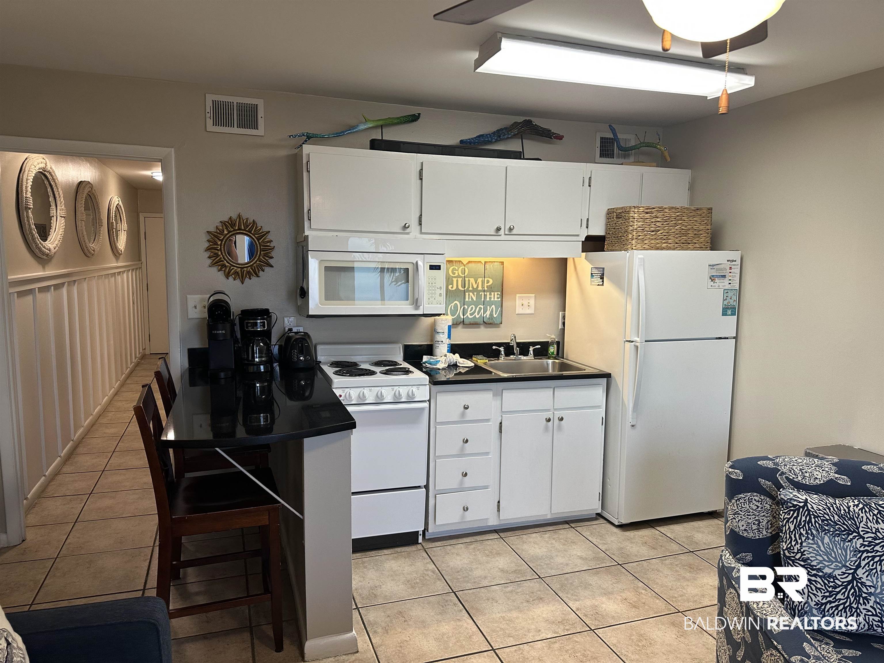 400 Plantation Road, Unit 2202 Gulf Shores, AL 36542 - Photo 18 of 26 Kitchen featuring white cabinets, white appliances, light tile patterned floors, and dark countertops