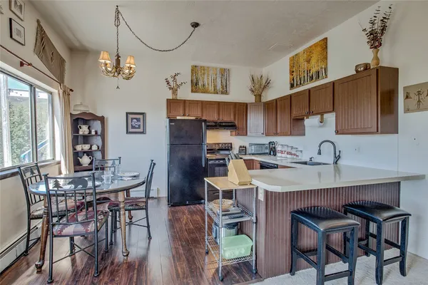 a kitchen with stainless steel appliances granite countertop a table chairs and a refrigerator