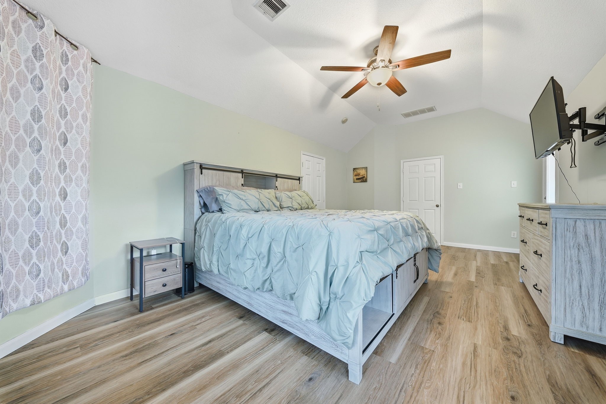 2223 Lazy Trail Path Court Spring, TX 77373 - Photo 12 of 23 Spacious bedroom with vaulted ceiling, featuring a stylish bed set, wood-look flooring, and a ceiling fan for comfort.