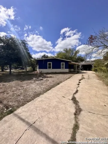 a view of house with yard and trees in the background