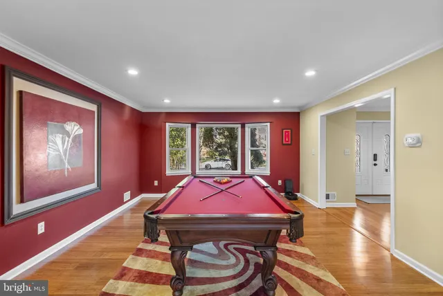 a living room with furniture pool table and wooden floor