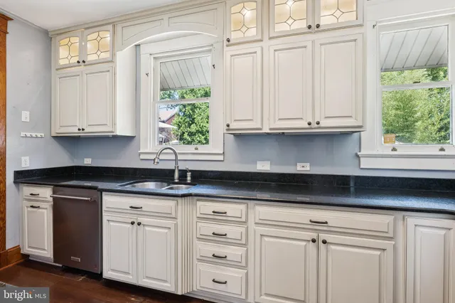 a kitchen with stainless steel appliances granite countertop white cabinets granite counter tops and a window
