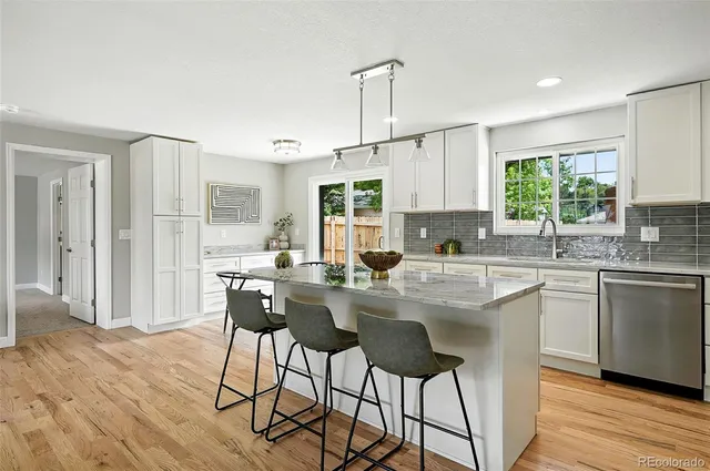 a kitchen with stainless steel appliances granite countertop a stove a sink dishwasher and a refrigerator with wooden floor