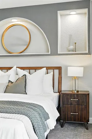 a bedroom with a bed a mirror and lamp