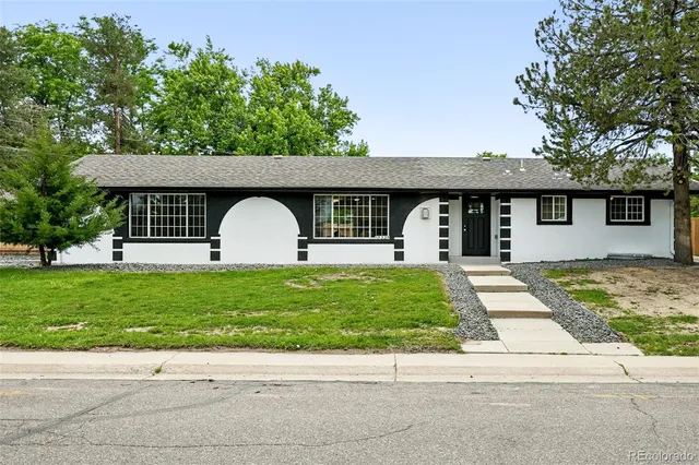 a front view of a house with a garden and trees
