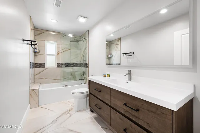 a bathroom with a sink a toilet a mirror and shower