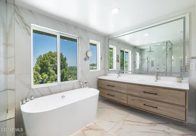 a bathroom with a granite countertop tub a sink and a large mirror