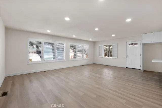 a view of an empty room with a window and wooden floor