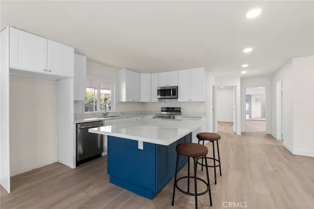 a kitchen with stainless steel appliances kitchen island granite countertop a table chairs sink and cabinets