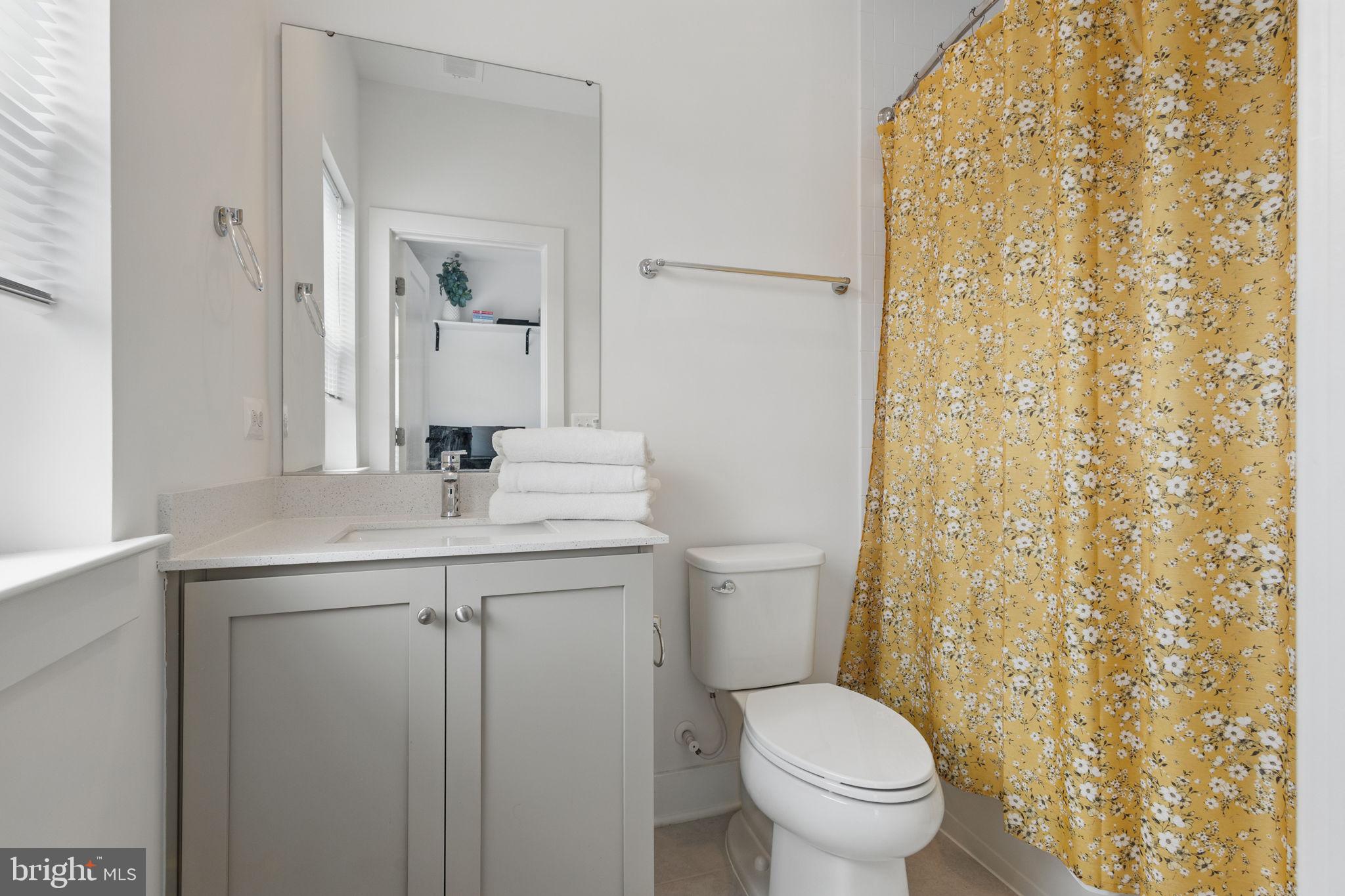 11239 Beaker Street Reston, VA 20190 - Photo 18 of 22 a bathroom with a granite countertop toilet a sink a mirror and a shower