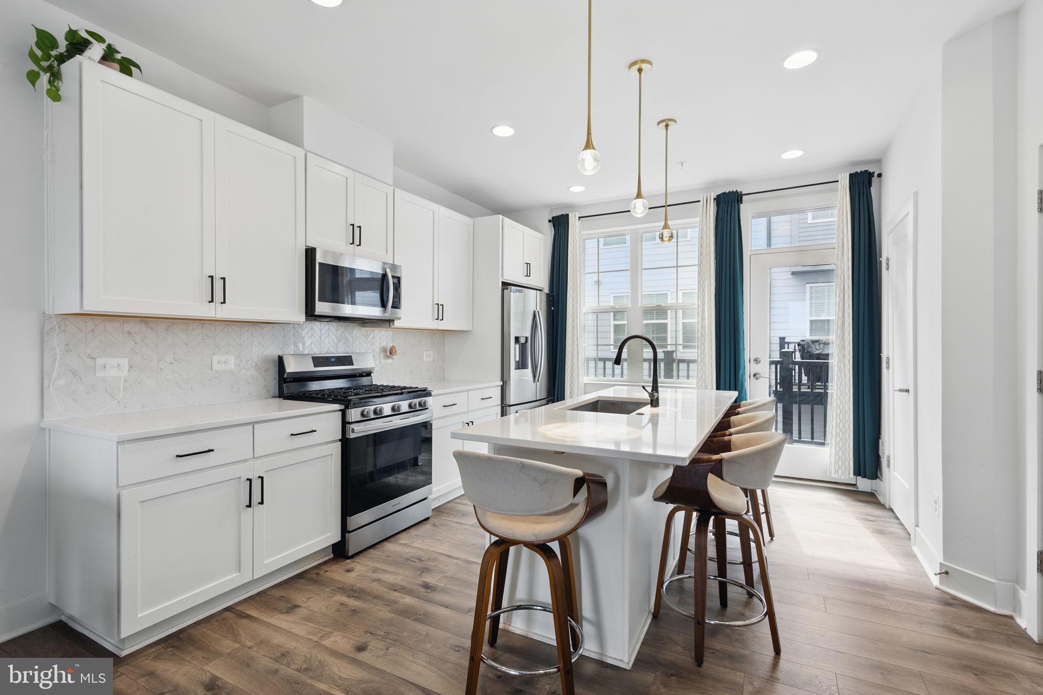 11239 Beaker Street Reston, VA 20190 - Photo 5 of 22 a kitchen with stainless steel appliances kitchen island a table chairs and a refrigerator