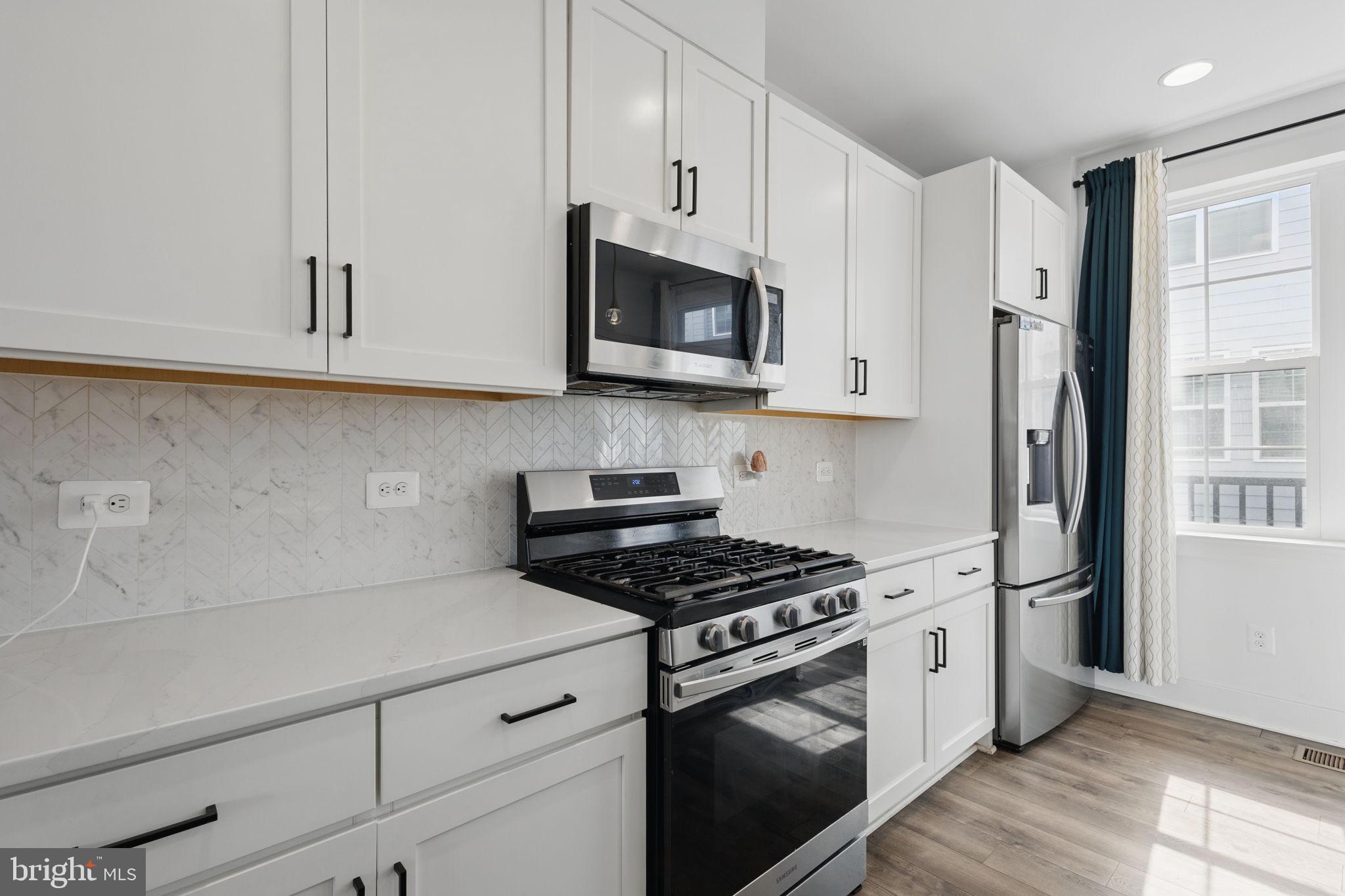 11239 Beaker Street Reston, VA 20190 - Photo 6 of 22 a kitchen with stainless steel appliances white cabinets and a stove a refrigerator a oven with wooden floor