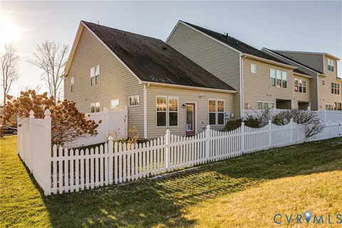 a view of a house with wooden fence next to a yard
