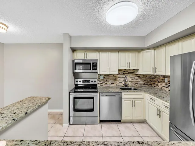 a kitchen with stainless steel appliances granite countertop a stove a sink and a refrigerator