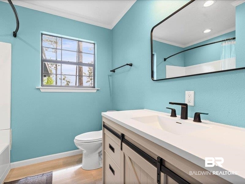 3160 Old Castleberry Road Brewton, AL 36426 - Photo 11 of 36 Modern bathroom featuring a single vanity with a white countertop and integrated sink, matte black fixtures, and wood-finish flooring