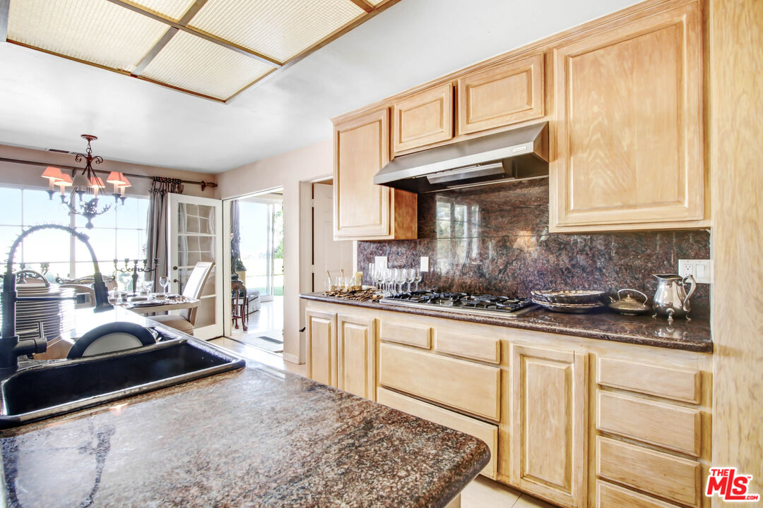 12535 Promontory Road Los Angeles, CA 90049 - Photo 13 of 42 a kitchen with granite countertop a sink a stove and cabinets