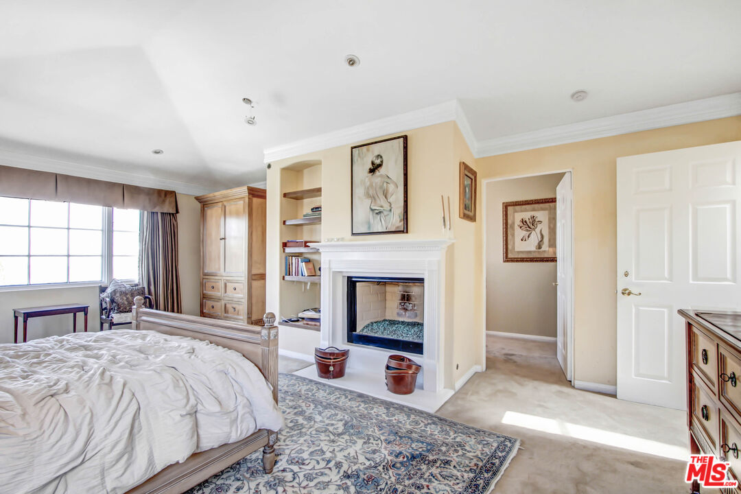12535 Promontory Road Los Angeles, CA 90049 - Photo 28 of 42 a spacious bedroom with a bed and a fireplace