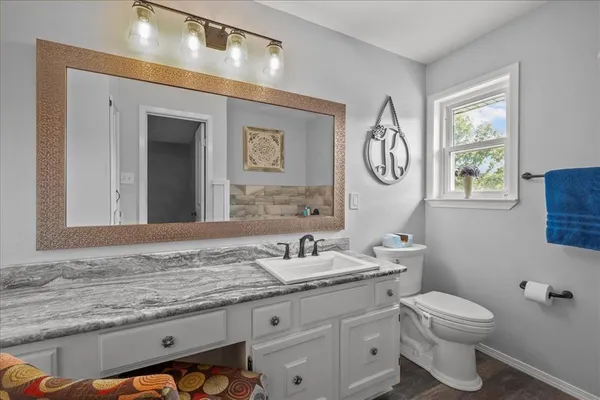 a bathroom with a granite countertop sink a toilet and a mirror