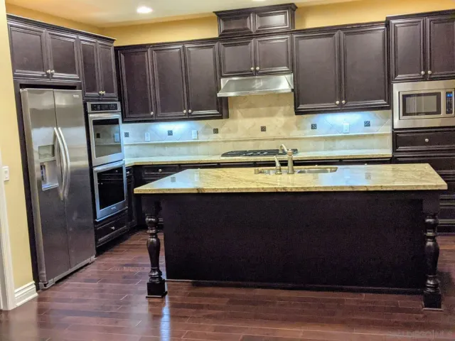 a kitchen with stainless steel appliances granite countertop a stove a refrigerator and a microwave