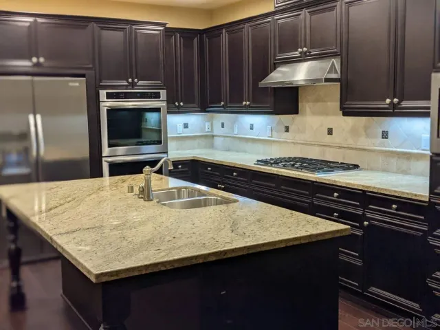 a kitchen with kitchen island granite countertop a sink a stove and cabinets