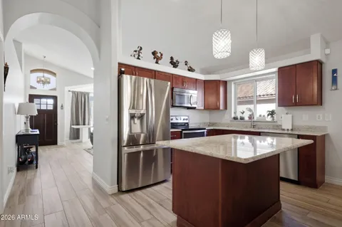 a kitchen with stainless steel appliances granite countertop a refrigerator a sink dishwasher a stove and white countertops with wooden floor