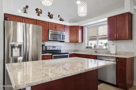 a kitchen with stainless steel appliances granite countertop a refrigerator a sink dishwasher a stove with wooden cabinets and floor