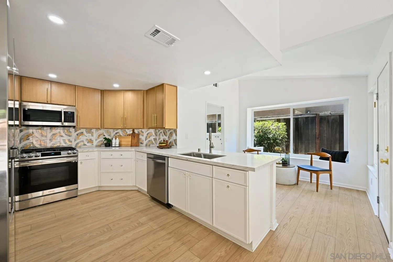 13010 Pomard Way Poway, CA 92064 - Photo 7 of 22 a kitchen with stainless steel appliances granite countertop a stove top oven a sink dishwasher a dining table and chairs with wooden floor