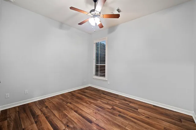 a view of a room with wooden floor and ceiling fan