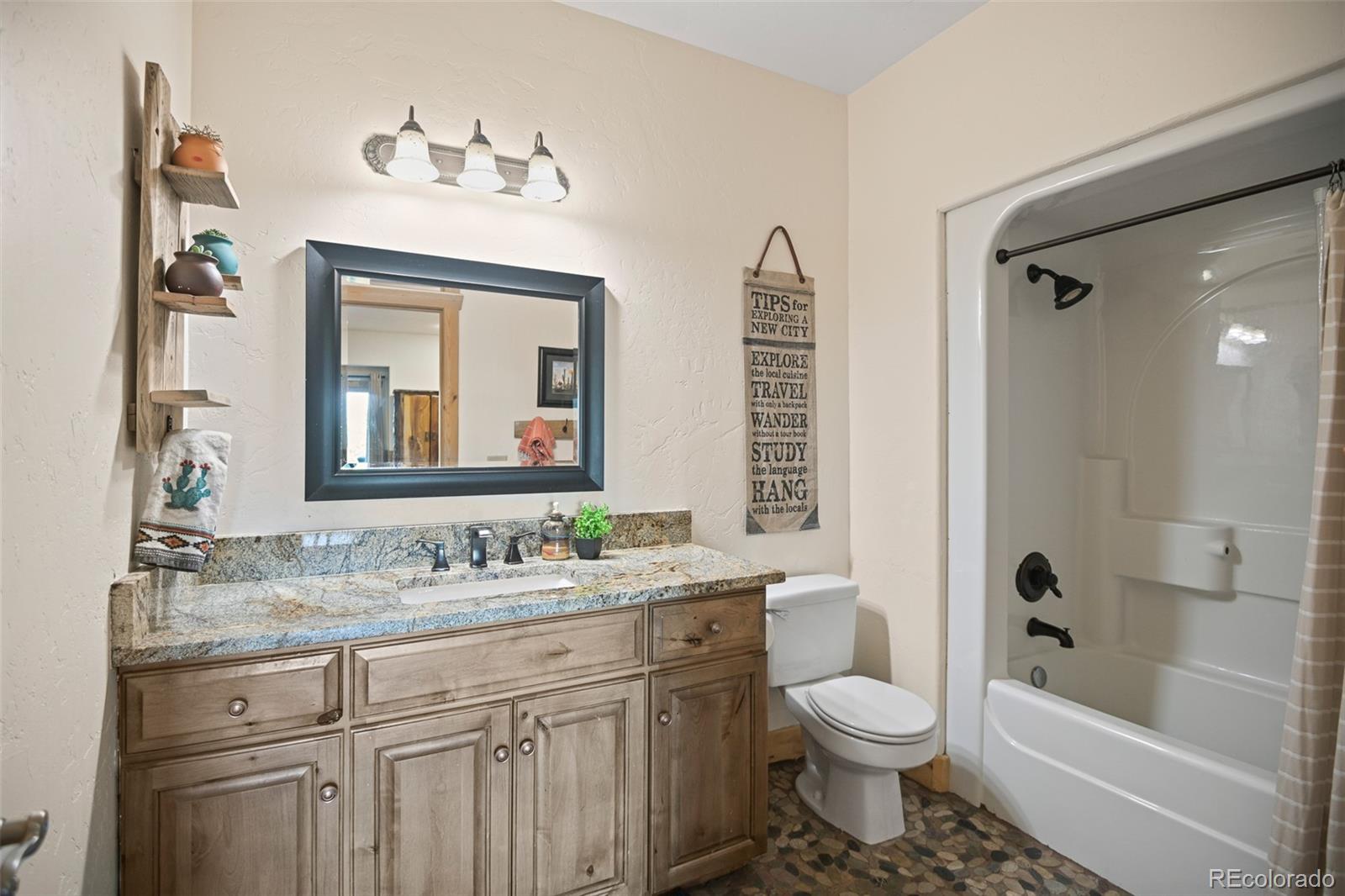 13434 Baird Road Conifer, CO 80433 - Photo 25 of 36 a bathroom with a granite countertop toilet a sink and a bathtub