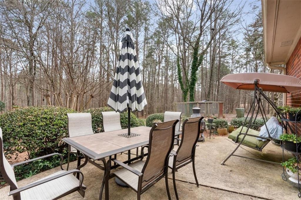 455 M M Sanders Road Buchanan, GA 30113 - Photo 44 of 65 a view of a patio with table and chairs under an umbrella with large trees