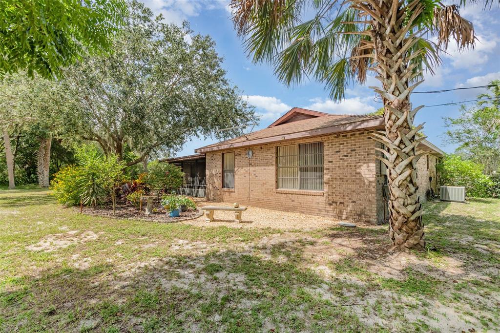 155 11th Avenue Osteen, FL 32764 - Photo 25 of 42 a backyard of a house with table and chairs under an umbrella