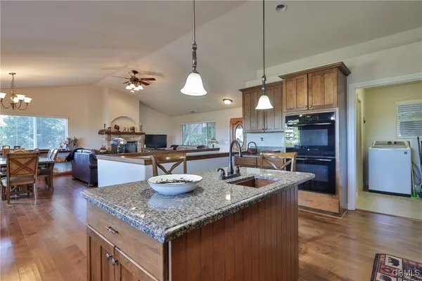 a kitchen with stainless steel appliances granite countertop a sink a stove and a wooden floors