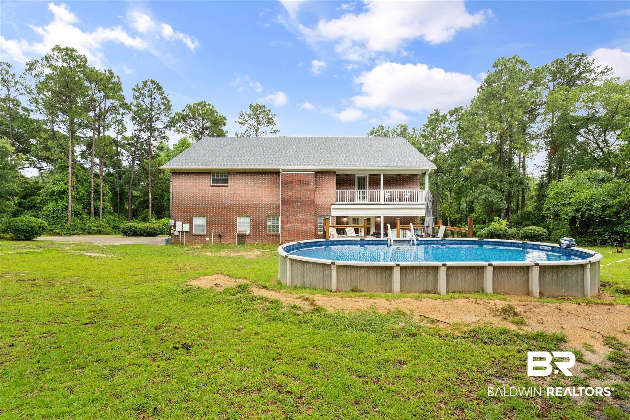 2300 Radcliff Road Saraland, AL 36571 - Photo 33 of 56 Back of house with a lawn, an outdoor pool, brick siding, and a balcony
