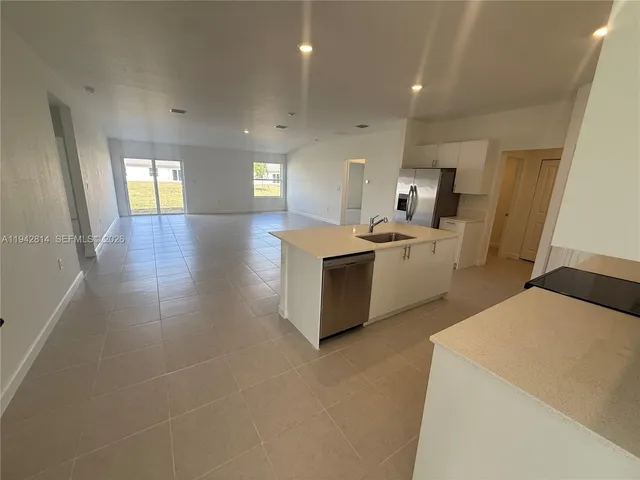 a kitchen with stainless steel appliances kitchen island granite countertop a refrigerator and a stove top oven