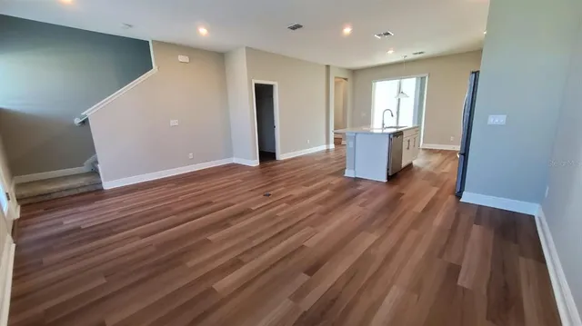 a view of a livingroom with wooden floor and staircase