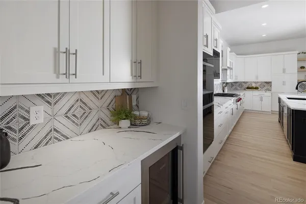 a kitchen with stainless steel appliances granite countertop a sink dishwasher stove and white cabinets with wooden floor