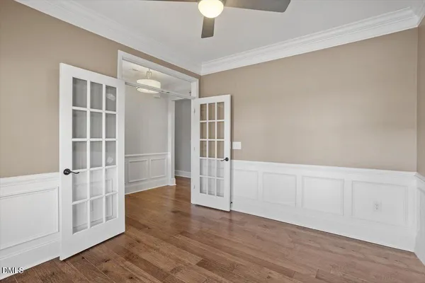 an empty room with wooden floor cabinet and windows