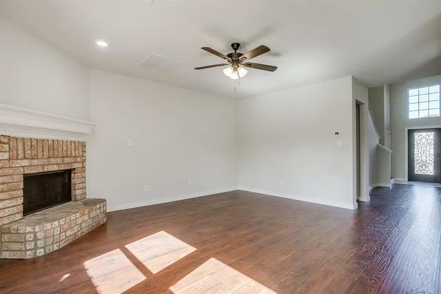 a view of an empty room with wooden floor and a fireplace