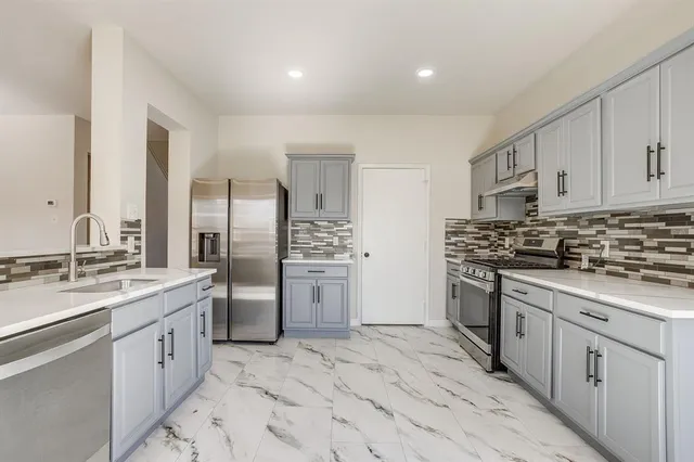 a kitchen with stainless steel appliances granite countertop a refrigerator sink stove and white cabinets