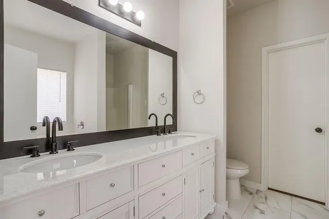 a bathroom with a granite countertop sink a toilet and a mirror