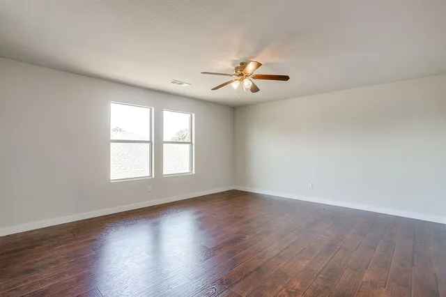a view of an empty room with a window and wooden floor